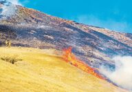 Firefighters watch flames climb a hill along Steptoe Canyon Road on July 22.