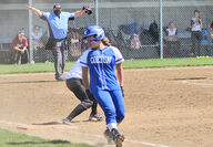 The umpire calls her run safe as Maddie Purnell sweeps past first base.
